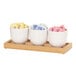 A Cal-Mil oak condiment organizer with three white cups holding different colored packets.