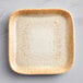 A square beige porcelain plate with a speckled surface.