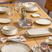 A set of round gray porcelain cups arranged on a wooden dining table with matching plates, bowls, and glassware.