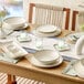 A set of round gray porcelain coupe plates arranged on a dining table with other tableware and decor.