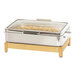 A stainless steel chafing dish with food inside on a wooden stand.