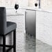 A Summit Appliance stainless steel beer dispenser on a counter next to a glass of beer.