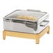 A stainless steel chafing dish with food inside on a wooden stand.