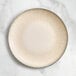 An Acopa Cape porcelain coupe plate with a light gray rim on a marble surface.