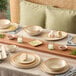 A round beige porcelain coupe plate displayed on a set dining table.