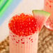 A glass of red liquid with red Fanale watermelon popping boba.