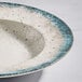 A round gray porcelain wide rim bowl with a speckled design and blue-gray edge.