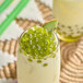 A glass of white liquid with Bossen kiwi bursting boba in it.