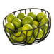A black Madison wire basket filled with limes on a counter.
