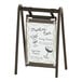 A black powder-coated metal frame holding a white sign with a black drawing of a martini glass.