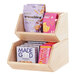 A blonde wooden counter merchandising display with two shelves holding snacks.