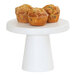 A Cal-Mil white melamine cake stand holding three muffins with crumbled topping.