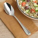 An Acopa Edgeworth stainless steel serving spoon in a bowl of food with vegetables.
