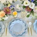 A table set with Sophistiplate Simply Eco sky blue dinner plates and flowers.