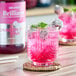 A glass of pink Monin Dragon Fruit Energy Drink with a dragon fruit garnish.