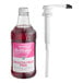 A white Monin bottle of pink liquid with a white cap next to a white pump tube.