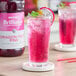 A glass of Monin Brilliance Dragon Fruit Pink Natural Energy Concentrate.