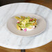 A Cal-Mil taupe melamine plate with food on a table.