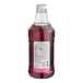 A close-up of a Monin Brilliance Dragon Fruit Pink Energy Concentrate bottle with a label.