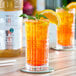 A close up of a glass of Monin Brilliance Sugar-Free Glacier Clear Natural Energy drink with a slice of orange and mint on top.