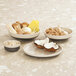 A table with three Cal-Mil Vienna brown and cream melamine bowls of food on it.