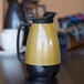 A Service Ideas Thermo-Serv coffee carafe with a black handle on a table.