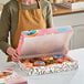A woman holding a multicolor "Enjoy" donut box filled with donuts.