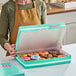 A woman holding a multicolor "Tasty" donut box full of donuts.