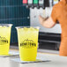 A clear plastic cup filled with a bright yellow-green citrus beverage over ice, branded with the Hometown Provisions logo.