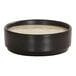 A small black melamine ramekin filled with a light-colored sauce.