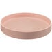 A pink round Cal-Mil Hudson melamine plate with a raised rim on a table.