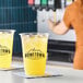 A clear plastic cup filled with iced yellow pineapple juice, branded with the Hometown Provisions logo.