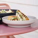 A Cal-Mil taupe melamine bowl/plate with a sandwich and salad on it.