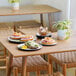 A wooden table with ivory and black Sophie Melamine pasta bowls on it.