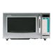 A silver Sharp commercial microwave with a black rectangular screen with white text.