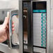 A person using a Sharp stainless steel commercial microwave.