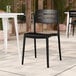 A black resin side chair with a slat back design, suitable for indoor or outdoor use.