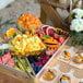 A BWOOD serving tray of fruit and sandwiches on a table outdoors.