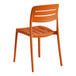 A terracotta-colored resin side chair with a slatted back and seat.
