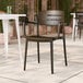 A brown resin arm chair with a slat back design.