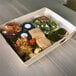 A VerTerra Balsa Wood tray with food and drinks on a bed.