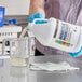 A person in blue gloves pouring CLR Pro Max Industrial Degreaser from a jug into a measuring cup.