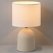 A 15-inch ceramic table lamp with a light concrete finish and a white linen shade.