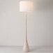 A wood-toned floor lamp with a cotton shade and an on/off rotary switch on the socket.