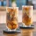 A pair of glasses with Numilk cashew milk iced coffee on a table.