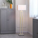 A gold floor lamp with a white linen shade and a faux marble base.