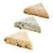A close up of a triangular scone with raisins and nuts.