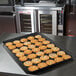 A black MFG fiberglass market display tray of cookies on a counter.