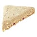 A triangular piece of Pillsbury raspberry white chunk scone with white chocolate and fruit.