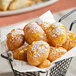 A basket of Kontos International Pastry Puffs on a table with powdered sugar.
